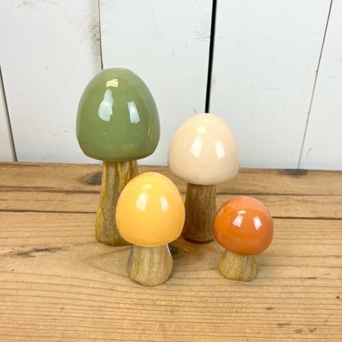 Set of four ceramic mushroom decorations on wooden surface.