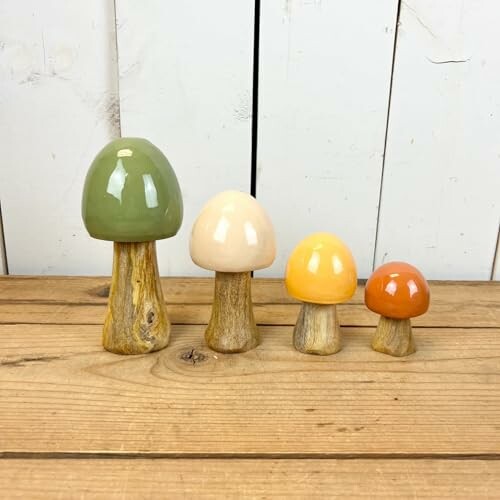 Four ceramic mushroom decorations in various colors and sizes on a wooden surface.