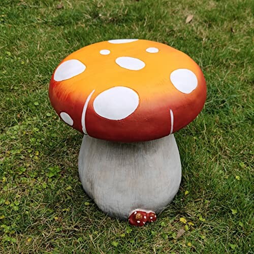 Large orange mushroom ornament with white spots on grass