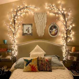 Cozy bedroom with fairy lights, framed pictures, and decorative pillows.