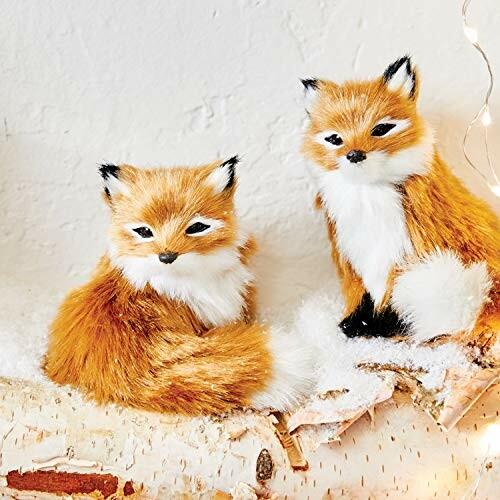 Two decorative fox figurines on a snowy surface.