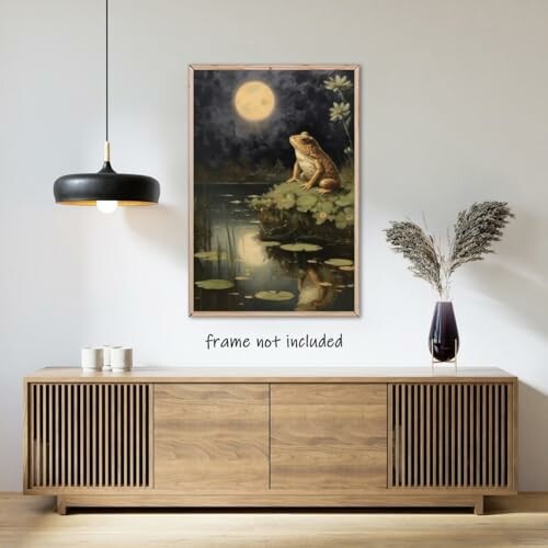 Art print of a frog on lily pads under a full moon, displayed above a modern wooden sideboard.