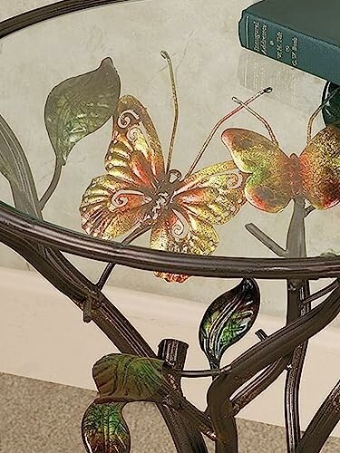 Glass table with metal butterfly and leaf design.