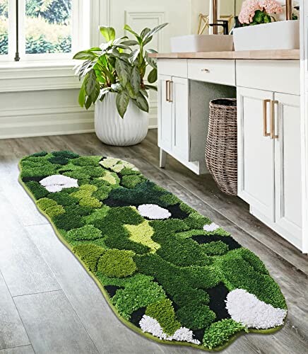 Green and white floral bath rug on wooden floor beside white cabinet with potted plant.