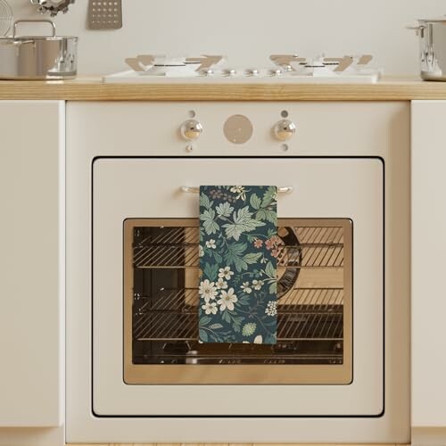 Kitchen oven with a floral towel hanging on the handle.