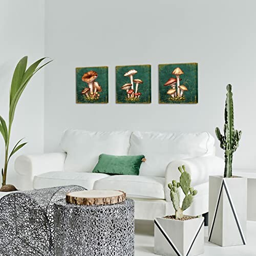 Living room with white sofa, green cushions, cactus plants, and mushroom artwork on wall.