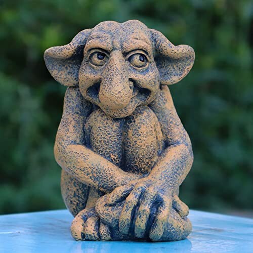 A small mischievous troll statue sitting with a playful expression.