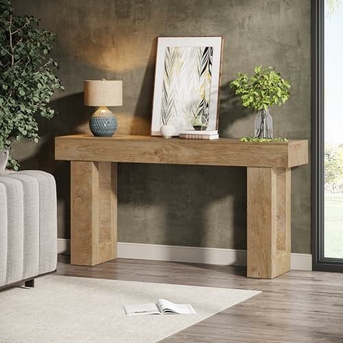 Modern wood console table with a lamp and framed art.