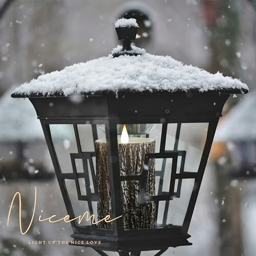 Snow-covered lantern with a lit candle inside.