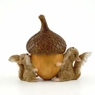 Two squirrel figurines holding a large acorn sculpture.