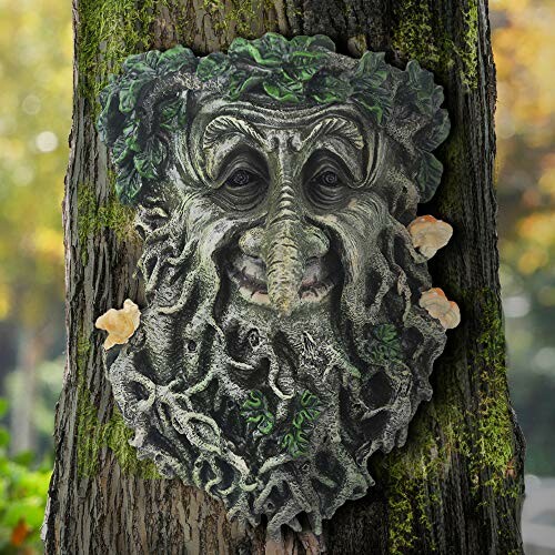 Tree trunk with a whimsical face sculpture and foliage.