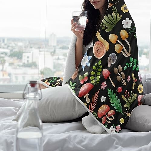 Woman sitting on bed with a colorful blanket, holding a glass of water.