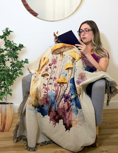 Woman reading on a chair with a mushroom-themed blanket.