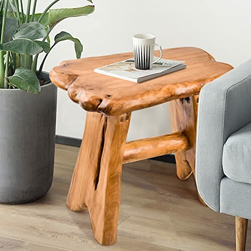 Wooden accent table with a mug and book next to a plant and sofa.