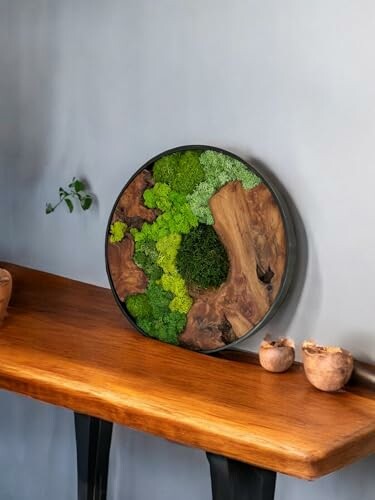 Round wooden wall art with green moss on a wooden table